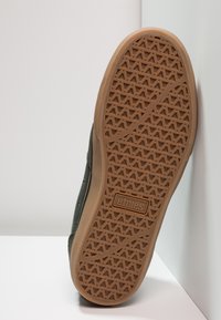 Pantofi Etnies cu o talpă din cauciuc maro, având un model triunghiular, material superior gri și logo în relief pe talpă.