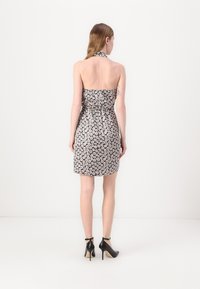 Strapless halter neck dress with a black and white floral pattern, fitted silhouette, and textured fabric. Worn with black high-heeled shoes.