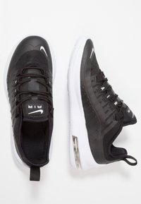 Zapatillas Nike negras con parte superior de malla, acentos blancos y una unidad de amortiguación de aire visible en la suela. Presentan un acabado texturizado y un diseño de cordones.