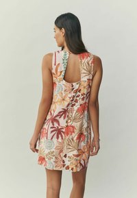 Lühike lilleline kleit, mis sisaldab erinevaid erksaid värve, võtmeauguga tagakülje disaini ja tekstuurse botaanilise mustriga kangast.