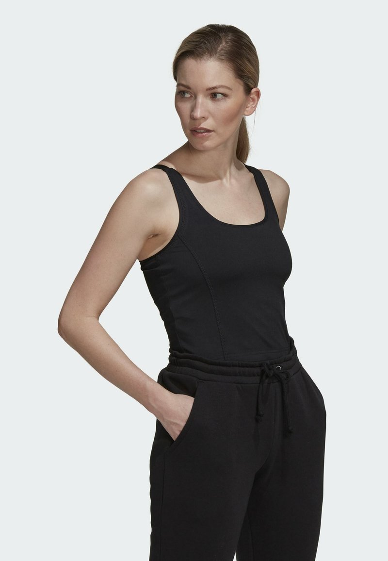 Schwarzes Tanktop mit breiten Trägern und rundem Ausschnitt, kombiniert mit schwarzen Jogginghosen mit elastischem Bund und Seitentaschen.