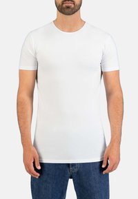 White short-sleeve t-shirt made of soft fabric, featuring a round neckline and a fitted design, paired with blue jeans.