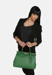 Grön läderhandväska med en strukturerad form, guldförsedda accenter och en texturerad yta. Har dubbla topphandtag och en låsdetalj.