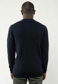 Dunkelblauer Strickpullover mit geripptem Muster und langen Ärmeln. Mit Rundhalsausschnitt und verlängertem Saum hinten.