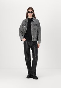 Gray denim jacket, black sweater, black faux leather pants, and black shoes. The jacket has button closure and chest pockets.