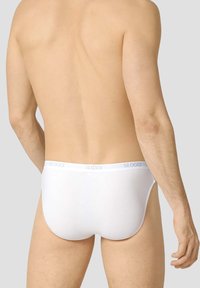 Slips Sloggi bianchi con una cintura morbida con logo, design semplice e texture liscia, visti da dietro su uno sfondo neutro.