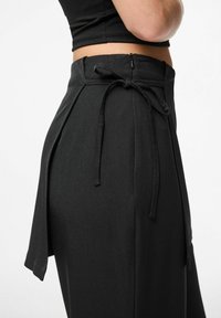 Pantaloni neri a vita alta con legatura laterale e chiusura con zip, realizzati in un tessuto morbido con una vestibilità sartoriale e una silhouette a gamba larga.
