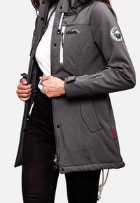 Veste softshell grise avec capuche, fermeture éclair à l'avant et poches, dotée d'accents de logo et d'un cordon de serrage à l'ourlet pour un ajustement réglable. Texture lisse.