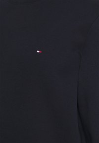 Marineblaues Baumwoll-Sweatshirt mit lange Ärmeln, ausgestattet mit einem kleinen, gestickten red, white and blue Logo auf der linken Brustseite. Glatte Textur.