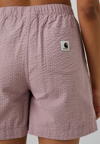 Lyserøde vævede shorts med et struktureret mønster, elastisk talje og en baglomme med et sort-hvidt logo-patch.