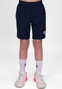 Marineblauwe shorts met een op maat gemaakte ontwerp, zakken en een logo-detail. Gecombineerd met witte sokken en grijze sneakers met oranje accenten.