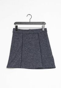 Jupe plissée bleu marine en tissu texturé, dotée d'une taille ajustée et suspendue à un cintre noir sur fond blanc.