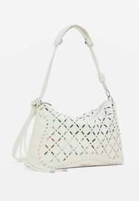 Borsa bianca con un intricato design a intaglio. Presenta dettagli in metallo, corpo testurizzato e chiusura con zip. Include una tracolla regolabile.