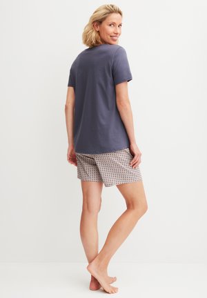 T-shirt en coton bleu marine à manches courtes, associé à un short à motifs avec un fond beige et des accents géométriques foncés.