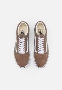 Bruna mockaskor med vita snören och sidremsor, med en klassisk låg design och en gummiyttersula med svart trim.