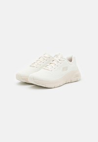 Scarpe da ginnastica bianche con tomaia in rete, suola ammortizzata, dettagli testurizzati e lacci piatti. Presentano un logo sul lato.