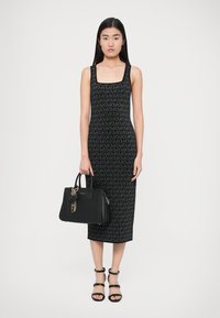 Μαύρο πλεκτό φόρεμα με τετράγωνη λαιμόκοψη και μοτίβο με λογότυπο MK σε όλο το ύφασμα. Συνδυάζεται με μαύρη τσάντα χειρός διακοσμημένη με γούρια και χρυσή αλυσίδα.