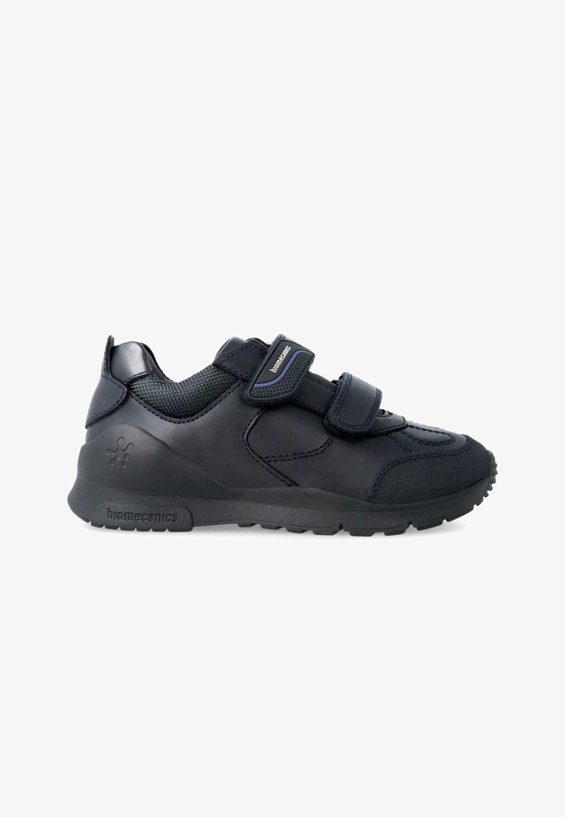 Chaussures de sport noires avec une tige en cuir lisse, des panneaux en mesh, des doubles sangles Velcro et une semelle en caoutchouc texturé pour l'adhérence.