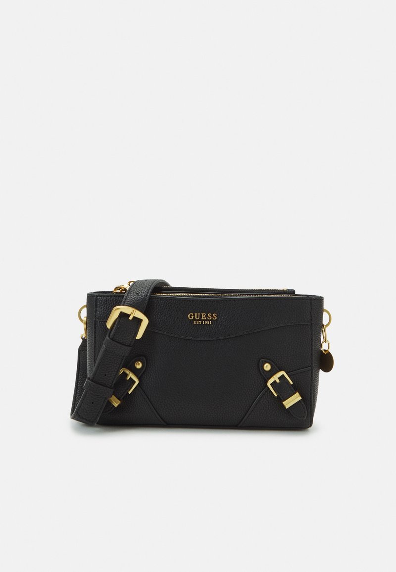 Sac en cuir texturé noir de Guess en bandoulière avec boucles dorées, fermeture éclair et sangle réglable sur fond blanc.