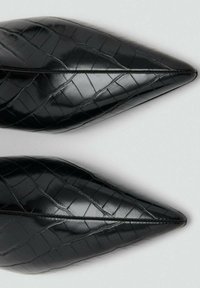 Bailarinas negras puntiagudas con un patrón texturizado de cocodrilo, que presentan cuero brillante y elegante y una costura suave a lo largo del centro.