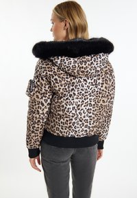 Giacca imbottita in stampa leopardata beige e marrone con colletto in pelliccia sintetica nera. Presenta una tasca con zip sulla manica sinistra e polsini a costine.