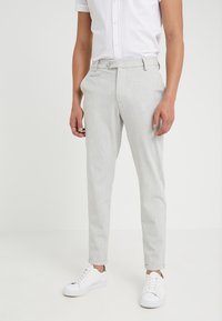 Lichtgrijze op maat gemaakte broek met een gestructureerde afwerking, voorzien van een vlakke voorkant, ri loops en zijzakken, gecombineerd met witte sneakers.