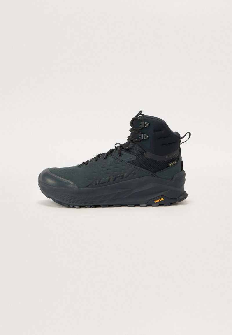 Svart vandringskänga med texturerad yta, hög ankelstöd och Vibram-sula. Har förstärkt snörning och ett ventilerande överdel.