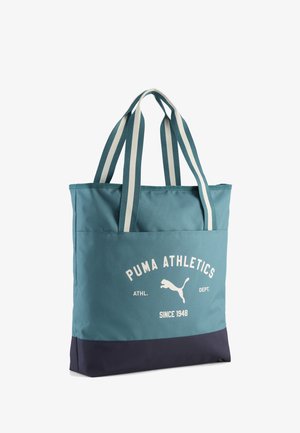 Sac fourre-tout Puma bleu et marine avec poignées à rayures blanches et texte ainsi que logo "PUMA ATHLETICS ATHL. DEPT. SINCE 1948" sur la poche avant.