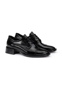 Scarpe eleganti in pelle nera con finitura lucida, dotate di punta a cappuccio, dettagli brogue e lacci piatti, su un tacco basso impilato.
