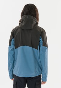 Vattentät jacka med en blå nederdel och mörkgrå överdel med huva. Slät textur, minimal hårdvara och kontrasterande färgblock.