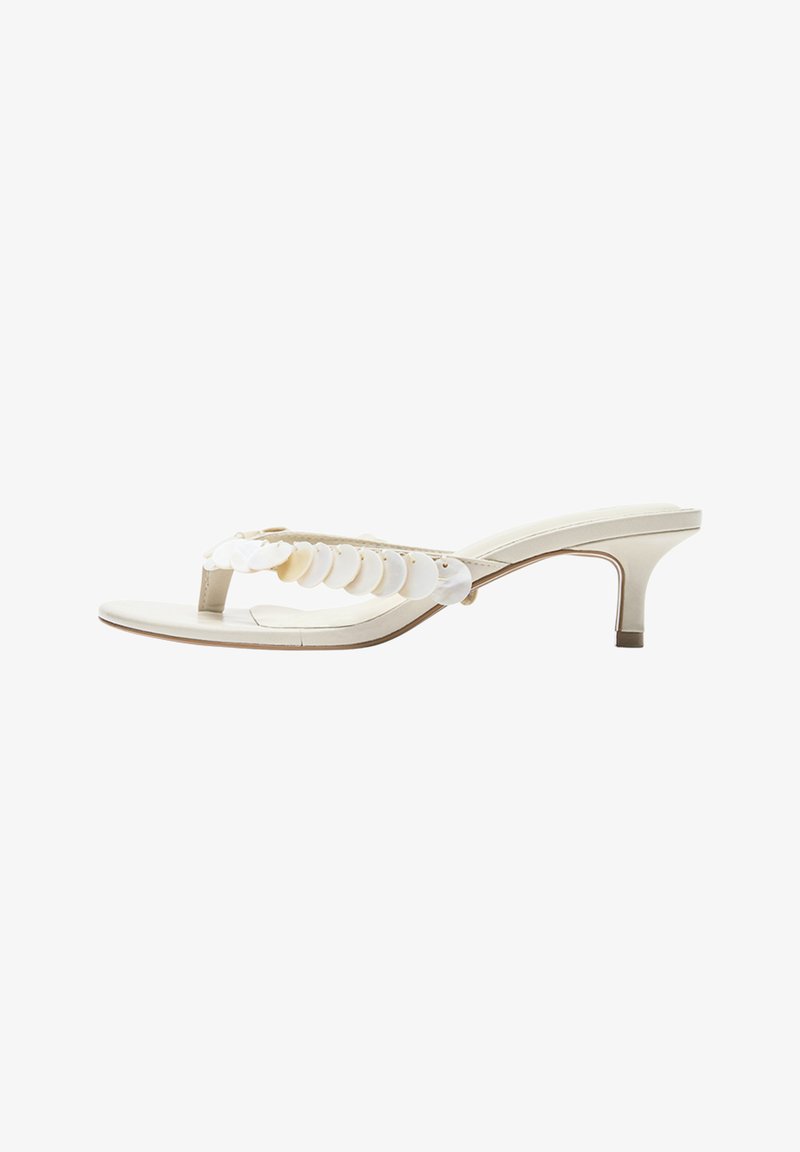 Sandale blanche à bout ouvert avec bride entre les orteils ornée de sequins ronds blancs superposés et talon fin de hauteur moyenne.