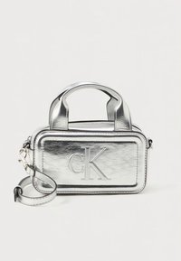 Silver metallic handbag with a rectangular shape, embossed 'CK' logo, dual handles, and a removable shoulder strap.