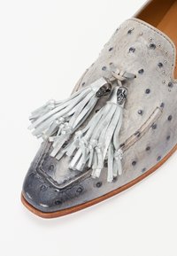Chaussure en cuir gris avec motif embossé, pampilles argentées et accents de crâne. Elle présente un bout pointu et un design épuré.