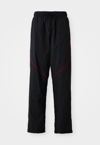 Zwarte sportbroek met een gestructureerde afwerking, voorzien van een trekkoord in de taille, rode accentlijnen en een losse pasvorm.