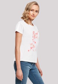 White cotton t-shirt with a round neckline, short sleeves, featuring pink floral graphic and Japanese text on the front.