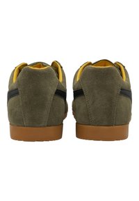 Sneaker in suede verde con suola in gomma marrone, dettagli neri e fodera gialla, con forma arrotondata e collarino imbottito.