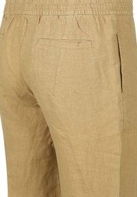 Beige linnen broek met een elastische tailleband, voorzien van twee achterzakken en een gladde textuur, die een casual ontwerp benadrukt.