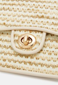 Borsa intrecciata texture in crema e beige con una chiusura dorata e una rifinitura liscia pallida. Presenta una forma rettangolare e strisce orizzontali.