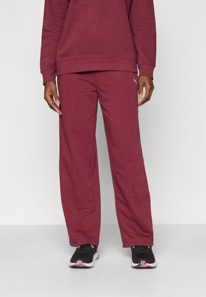 Bordeaux joggebukser laget av mykt stoff, med rett snitt, sømdetaljer og en liten logo på venstre side.