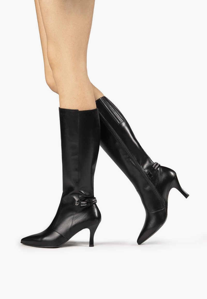 Bottes hautes en cuir noir jusqu'au genou avec un bout pointu et un talon moyen. Elles possèdent une fermeture éclair et une sangle ajustable à la cheville.