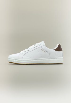 Zapatilla blanca de corte bajo con lengüeta trasera marrón, cordones blancos y texto "GAP EST. 1969" en dorado en el lateral.