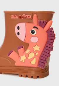 Botte de pluie en caoutchouc marron avec un design 3D de girafe rose et des accents orange et des étoiles jaunes. Semelle texturée pour une bonne traction.