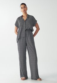Zwart-wit gestreept shirt en wijde broek set, gemaakt van zachte stof, met een kraag en een ontspannen pasvorm met zijzakken.