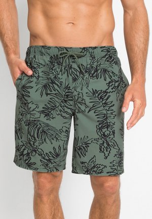 Shorts da bagno verdi con un motivo di foglie tropicali nere, dotati di una fascia elastica in vita e tasche laterali per maggiore comodità.