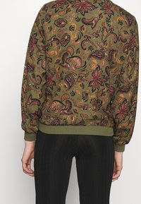 Olivgrön sweatshirt med flerfärgade blommönster och paisleymönster, ribbade muddarna och nederkanten samt en avslappnad passform.