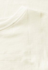 Hvid bomulds t-shirt med rund halsudskæring og subtile præget linjemønstre over stoffet, som skaber tekstur og visuel interesse.