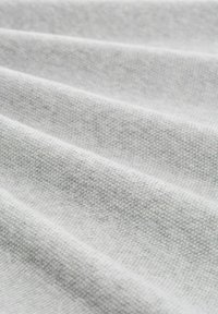 Lichtgrijze stof met een getextureerde weving, die zachte plooien vertoont. Het materiaal lijkt glad met een consistent, subtiel patroon overal.