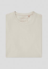 Jasnobeżowa koszulka wykonana z elastycznej bawełny, z okrągłym dekoltem i metką oznaczoną 'M'. Gładka tekstura z symbolami pielęgnacyjnymi nadrukowanymi wewnątrz.