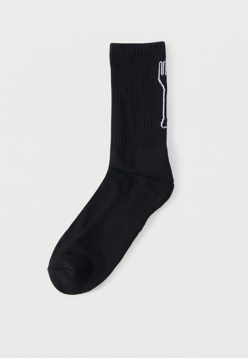 Calzino nero a coste fino a metà polpaccio con design bianco contornato che ricorda una forchetta verticale sul lato, mostrato su uno sfondo bianco neutro.