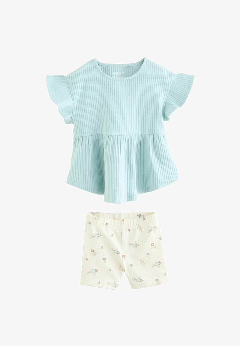 Haut bleu clair côtelé à manches courtes avec manches volantées, associé à un short crème à petits motifs floraux.